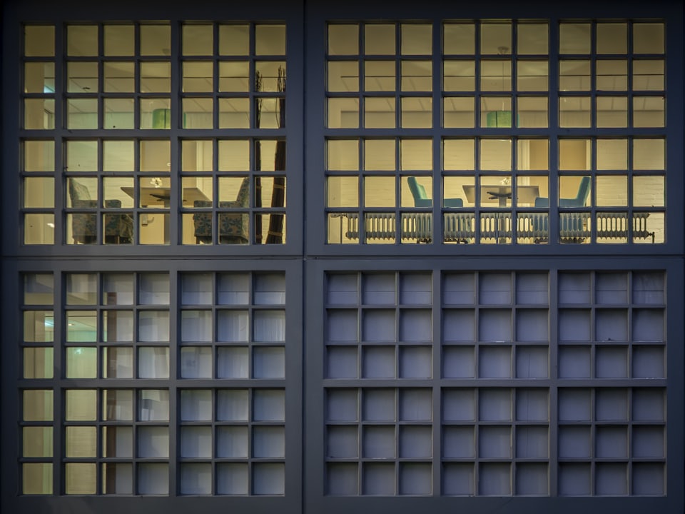 A tall window lit warm from inside, in a dark facade at night